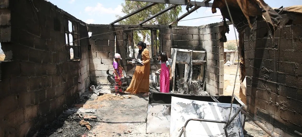West Bank closures: A mother and her children go through belongings after a room in their home was burned in a settler attack in southern Hebron (file photo, July 2025)